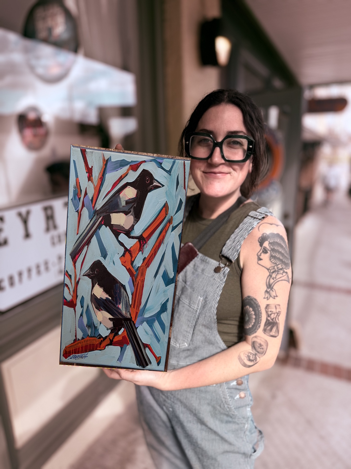 Gabby Smith holding her painting of two birds